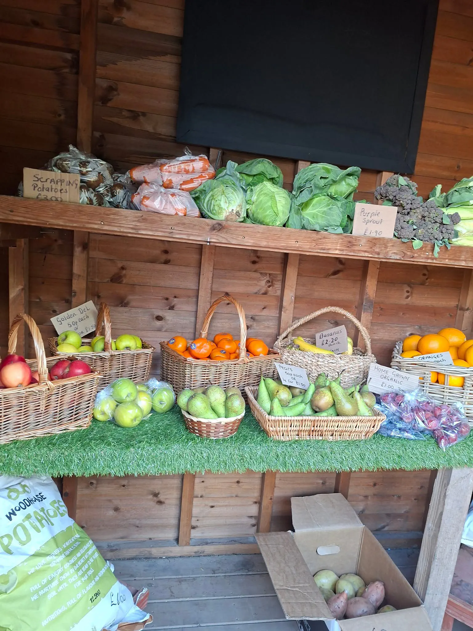 Baskets of apples, pears and oranges, with cabbages and carrots on the shelf in the fruit shed.