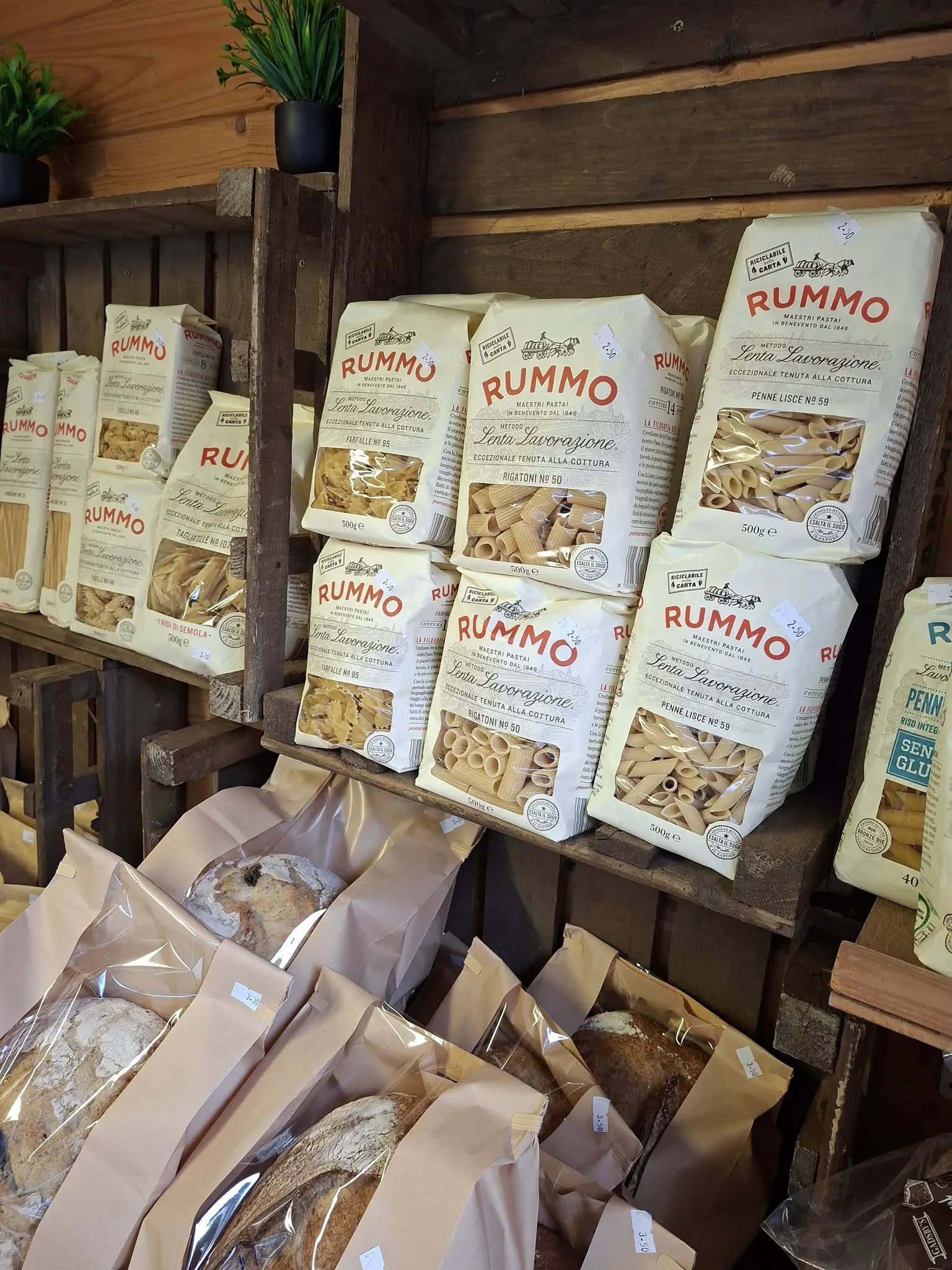 Packets of Rummo pasta on a wooden shelf, with loaves below.